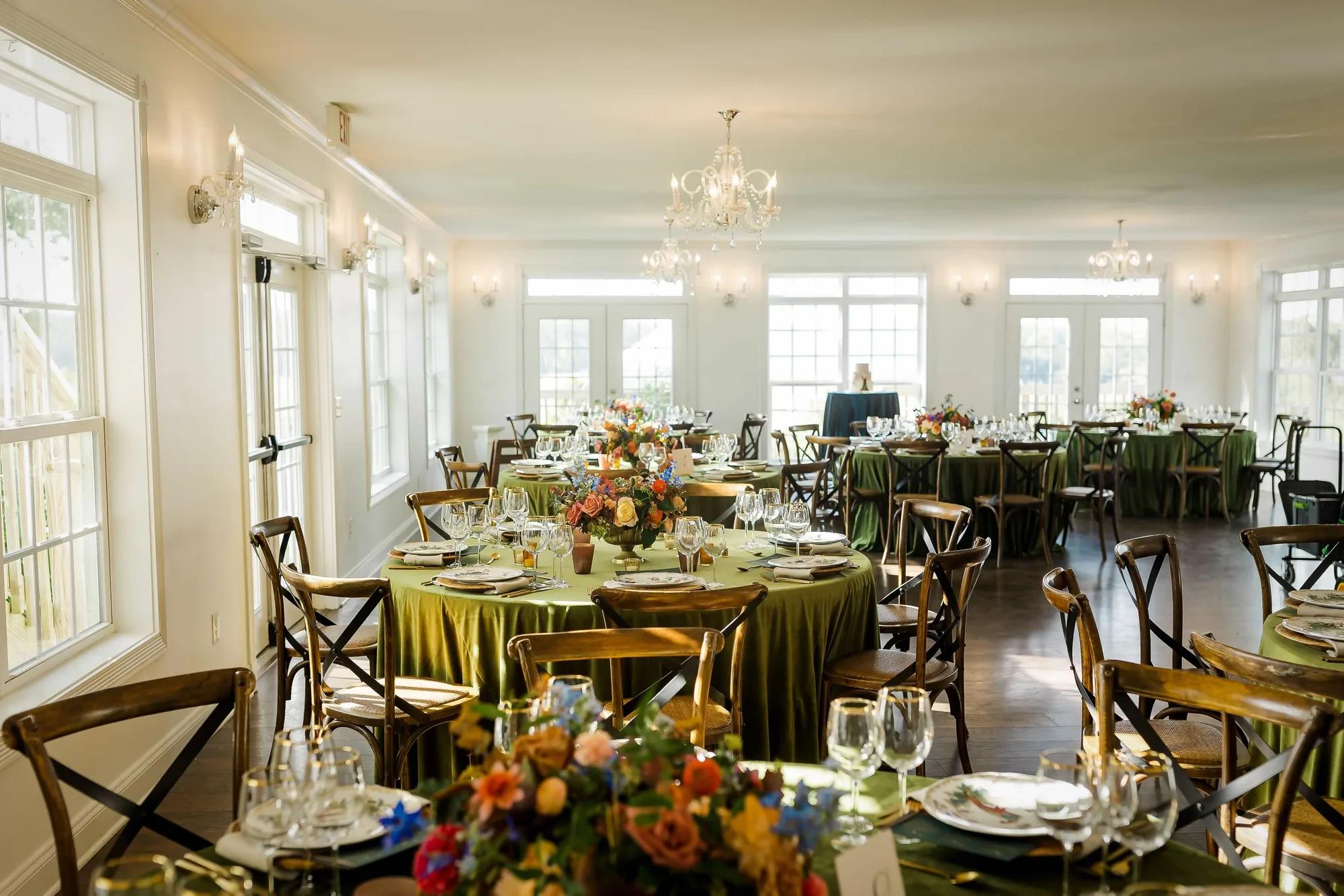 Elegantly set reception room at Rixey Manor with green velvet linens, colorful florals, and crystal chandeliers