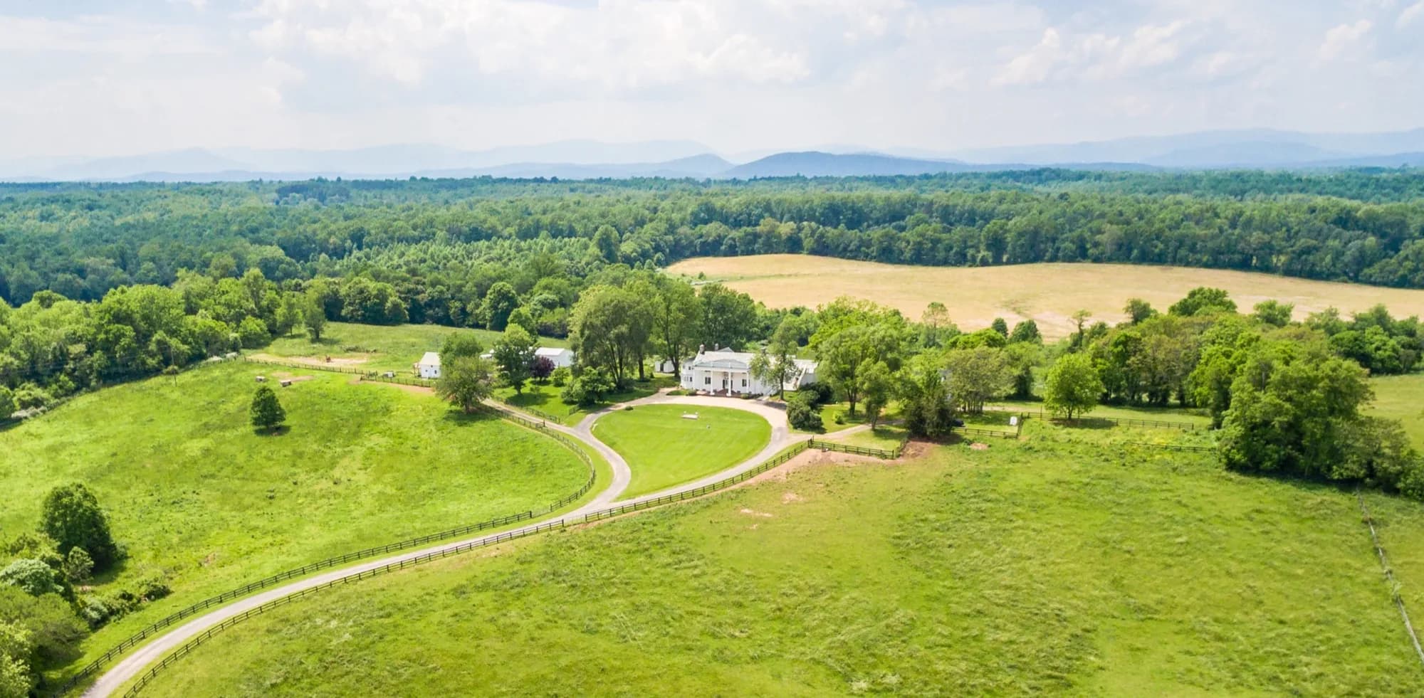 Aerial view of Rixey Manor estate surrounded by rolling green fields and Blue Ridge Mountains in rural Virginia