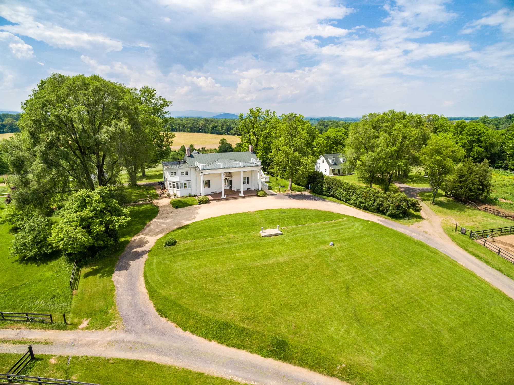 Aerial view of Rixey Manor's white estate home, sweeping green lawn, and circular drive in rural Virginia