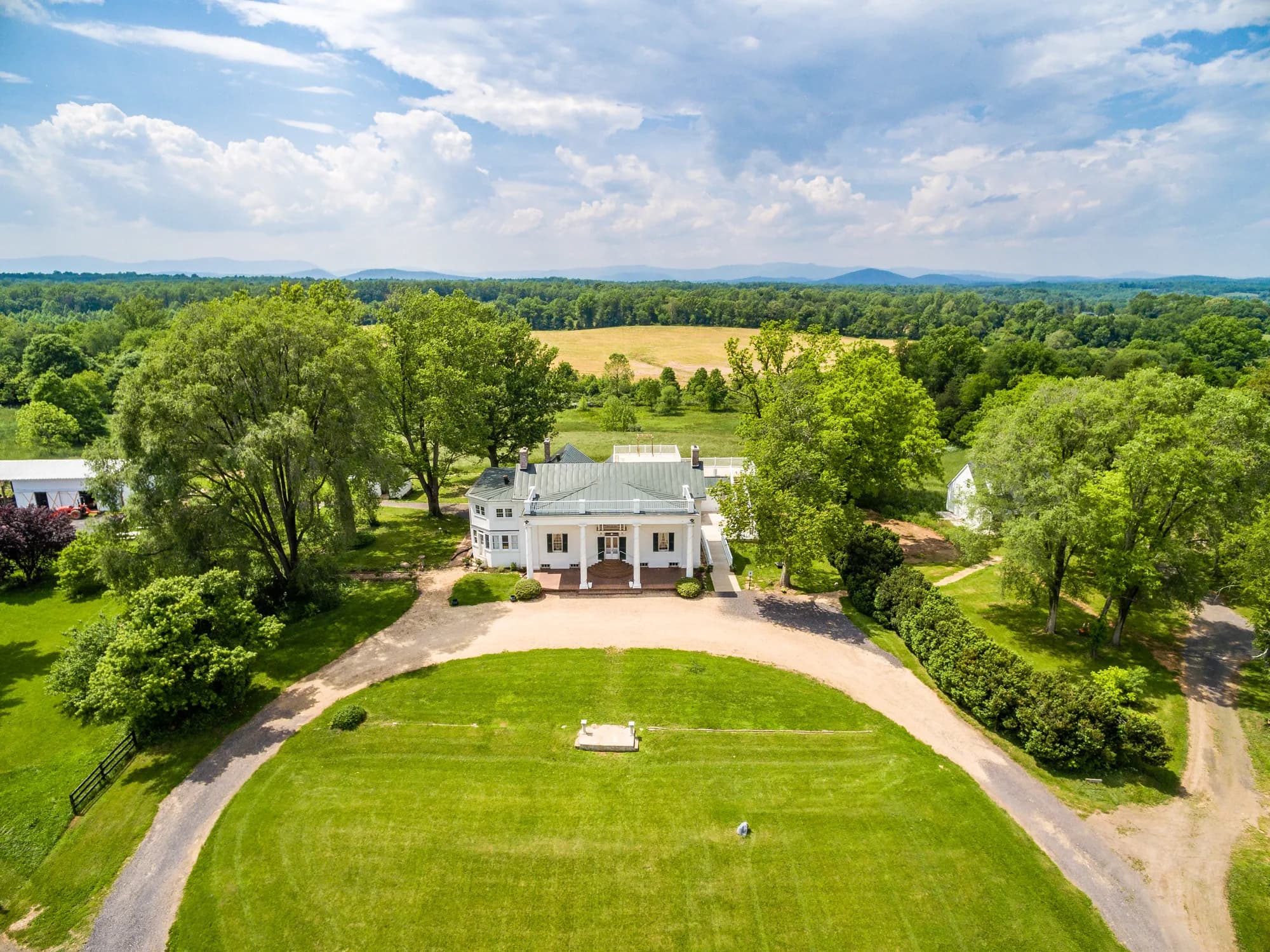 Aerial view of Rixey Manor estate, white columned mansion surrounded by lush grounds and Blue Ridge Mountains