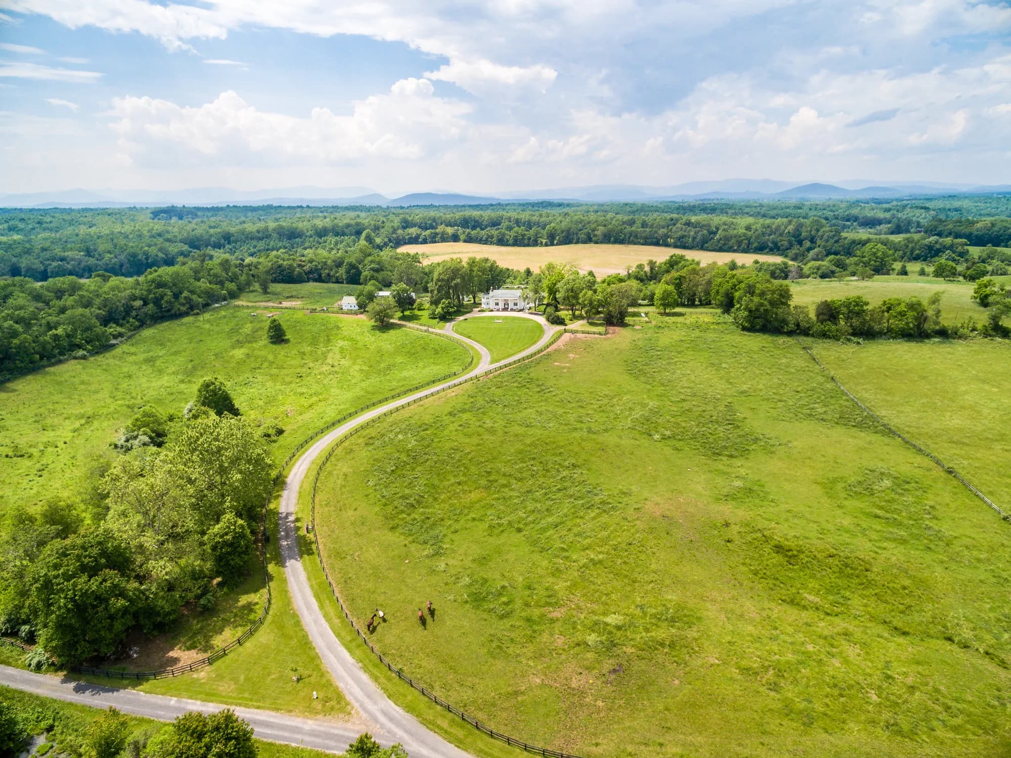 Aerial view of Rixey Manor estate with winding driveway, green pastures, and Blue Ridge Mountains backdrop