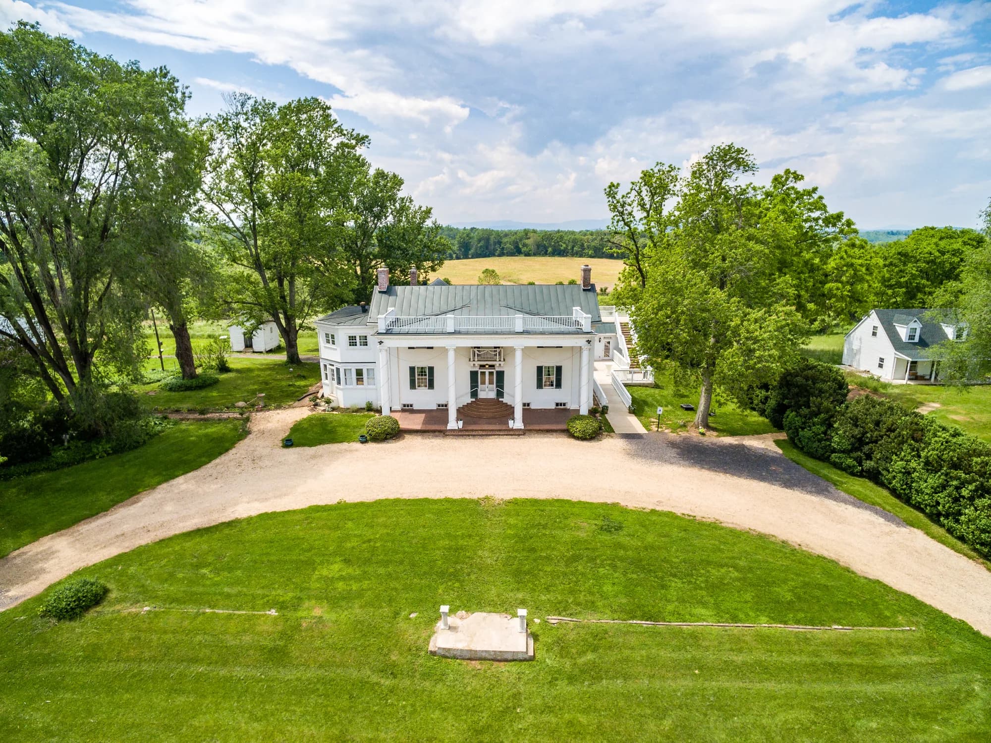 Aerial view of Rixey Manor historic white estate with columned portico, circular drive, and lush Virginia countryside.