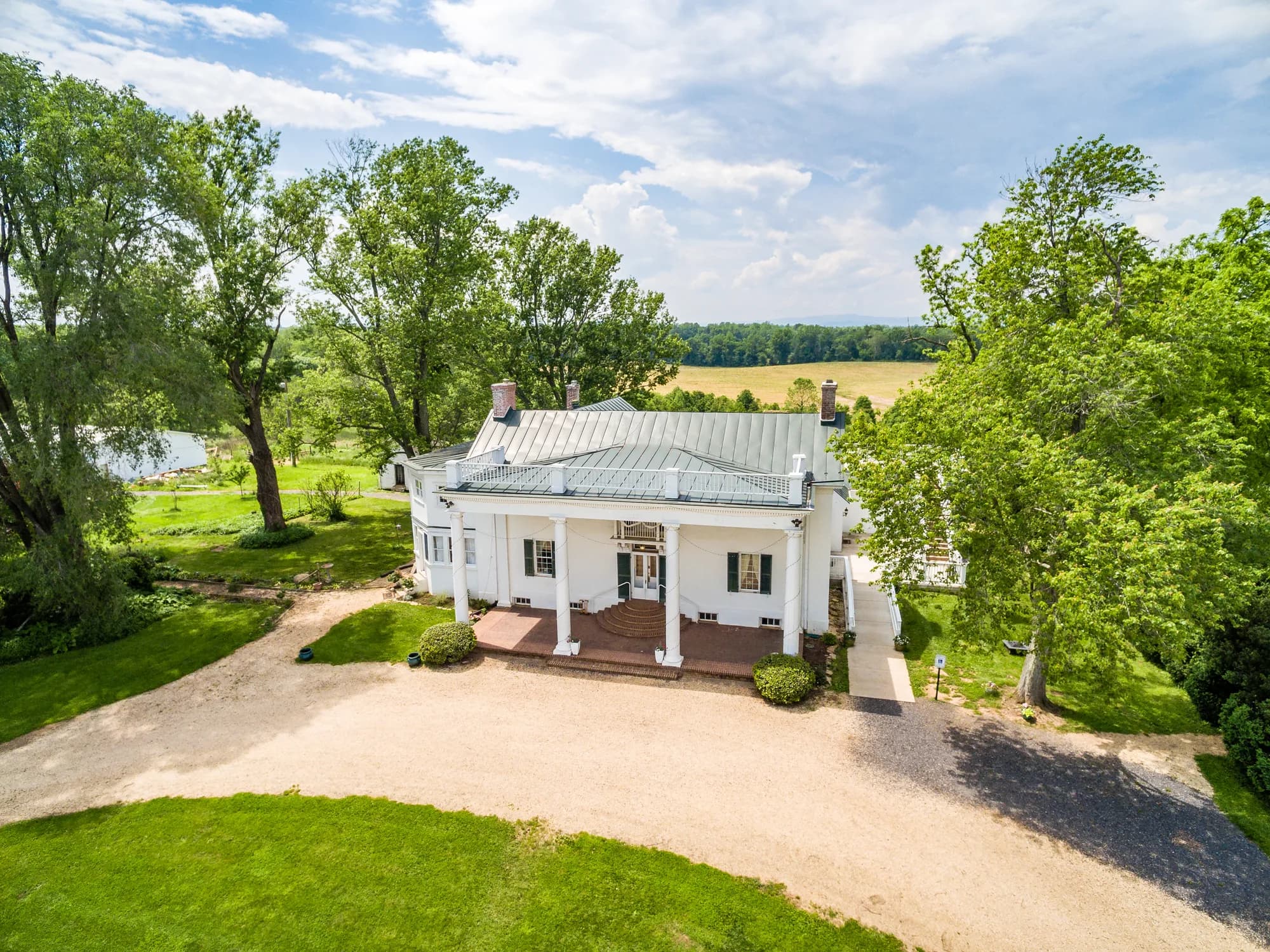 Aerial view of Rixey Manor's white columned estate surrounded by lush trees and open Virginia countryside