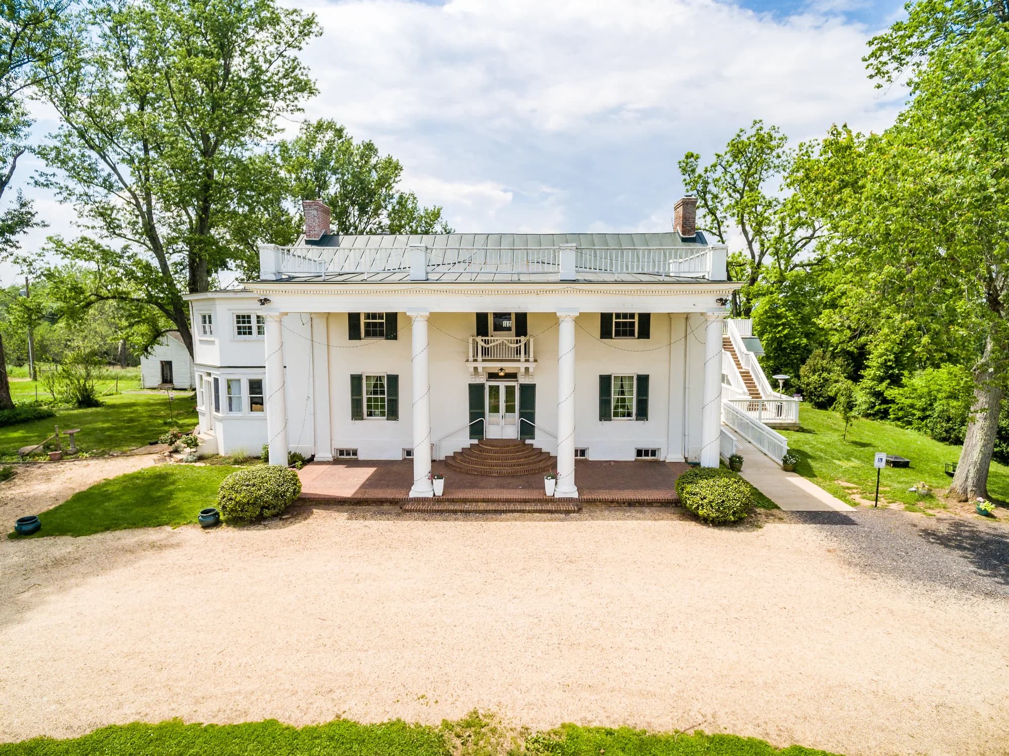 Aerial view of Rixey Manor's white columned antebellum facade surrounded by lush Virginia greenery
