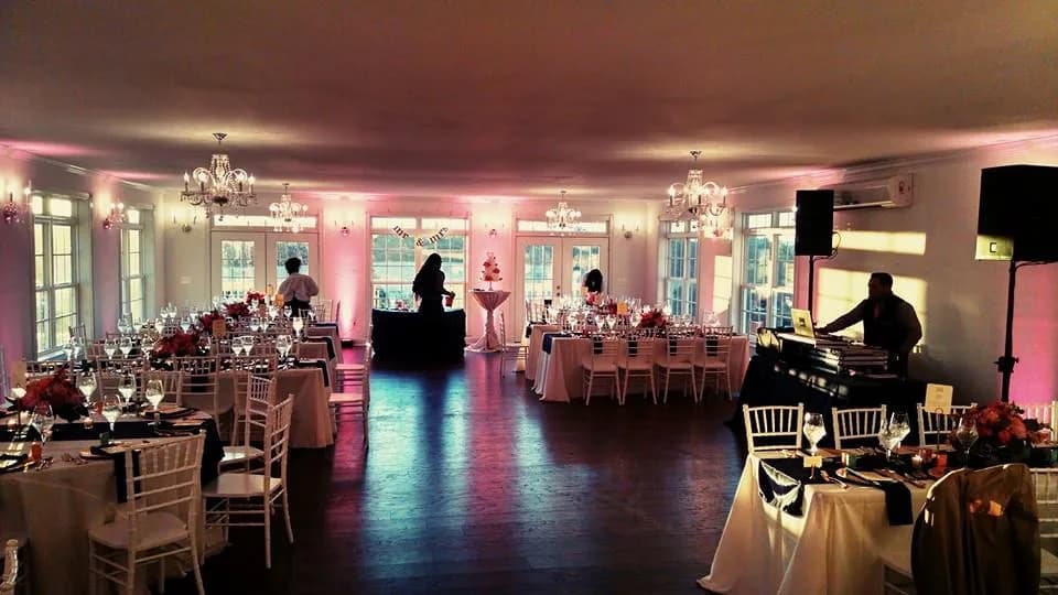Rixey Manor ballroom reception setup with pink uplighting, crystal chandeliers, and draped tables before guests arrive