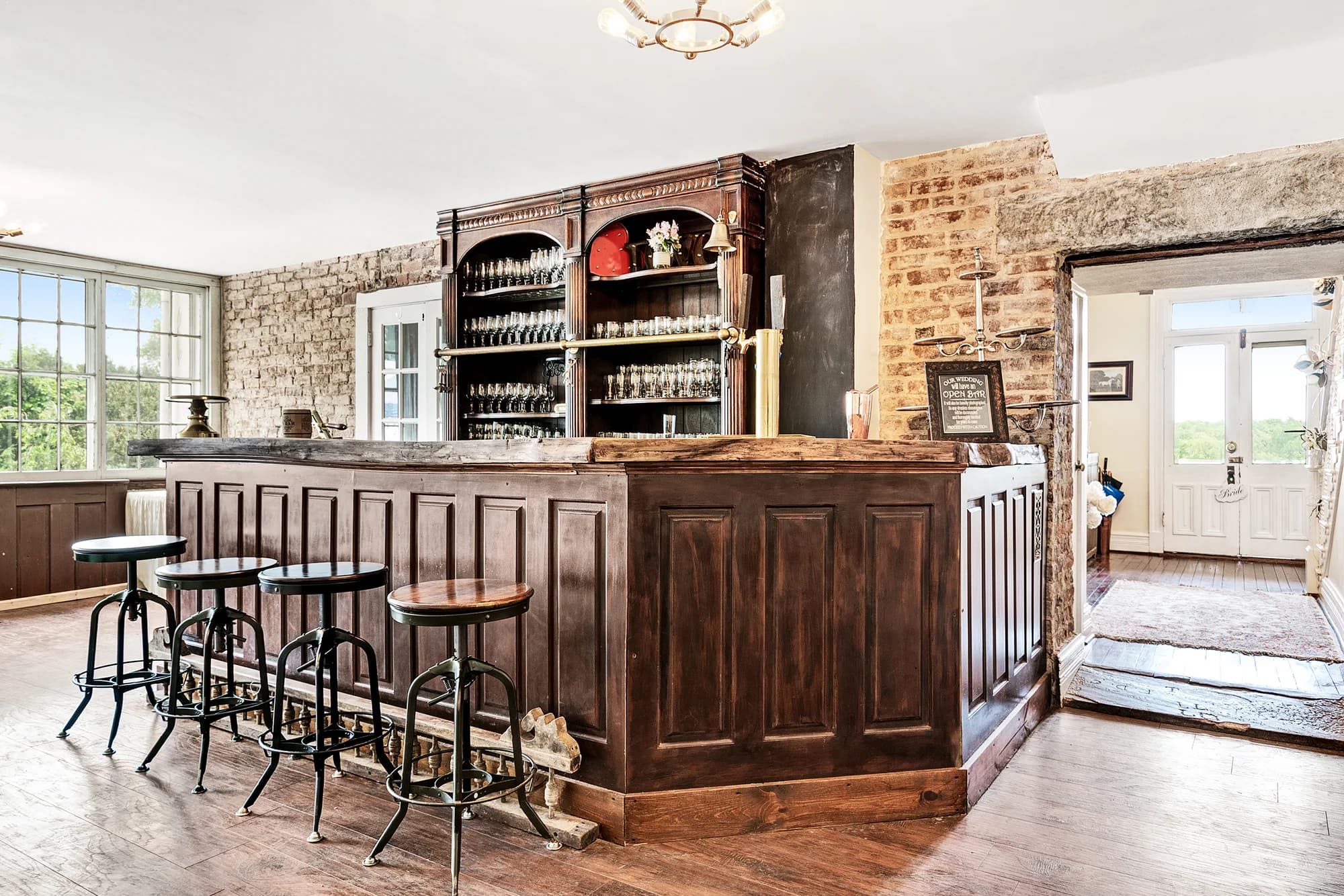 Rustic dark-wood bar with exposed brick walls and vintage back bar shelving inside Rixey Manor estate