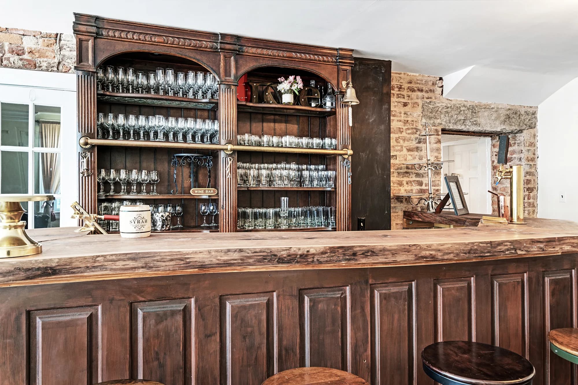Ornate dark wood bar with glassware-lined shelves at Rixey Manor's vintage pub-style bar area