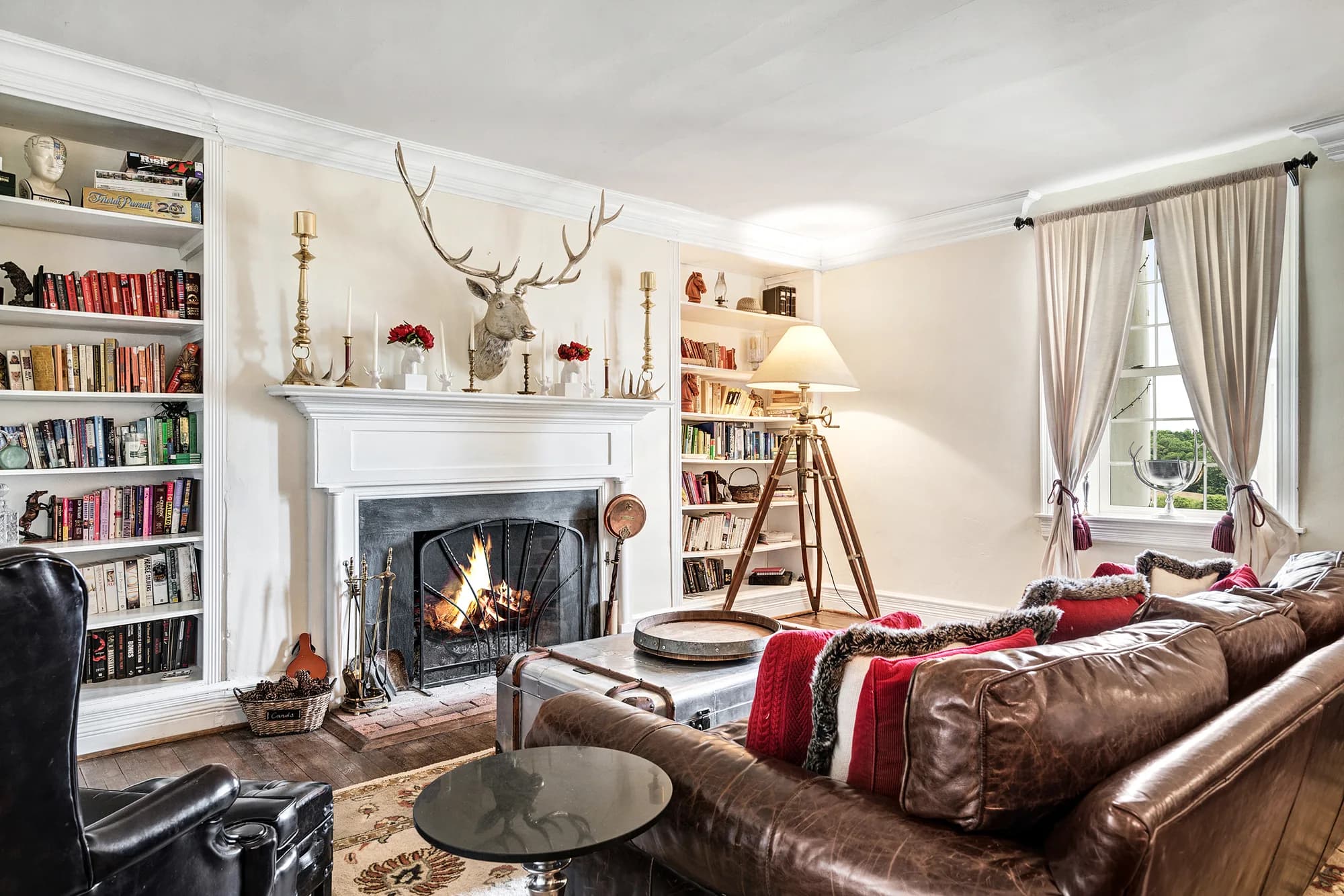 Elegant living room with fireplace, leather sofa, bookshelves, and holiday decorations at Rixey Manor