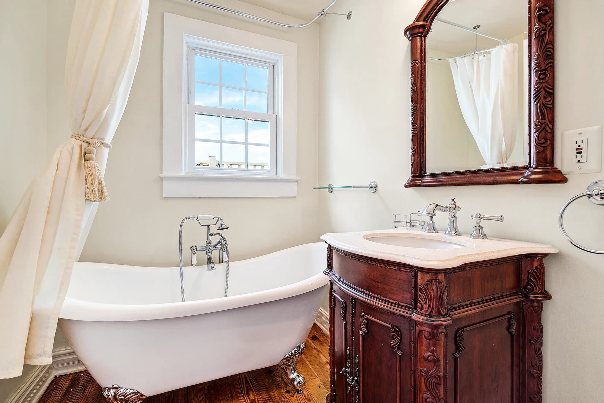 Ornate clawfoot soaking tub and carved mahogany vanity in a vintage bridal suite at Rixey Manor