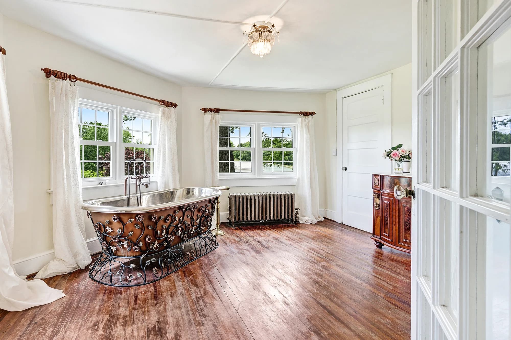 Ornate copper clawfoot soaking tub in a sunlit bridal suite with hardwood floors at Rixey Manor