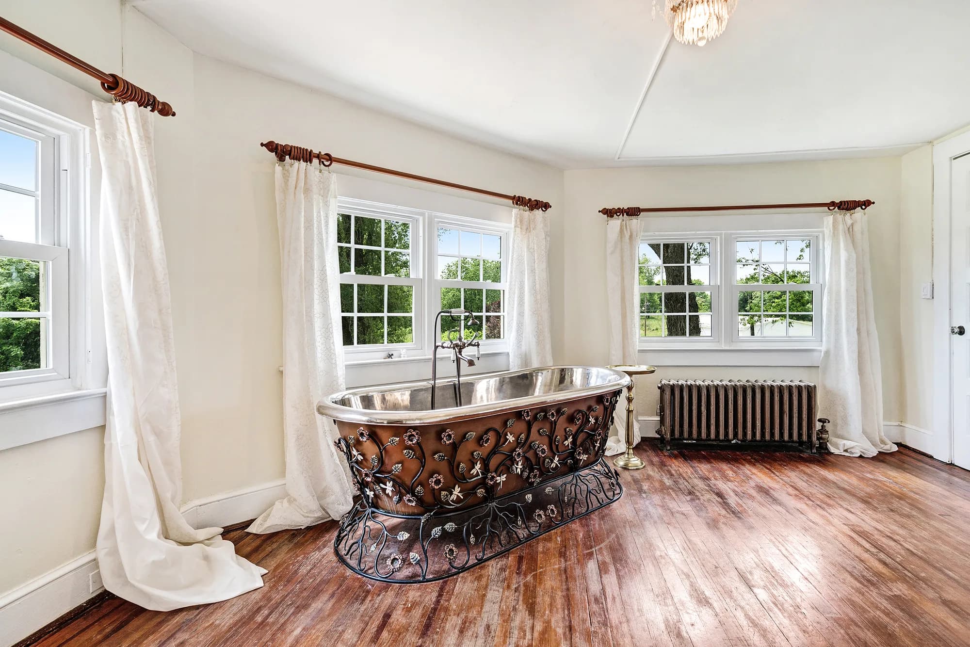 Ornate Victorian freestanding bathtub with wrought iron scrollwork in a sunlit bridal suite at Rixey Manor