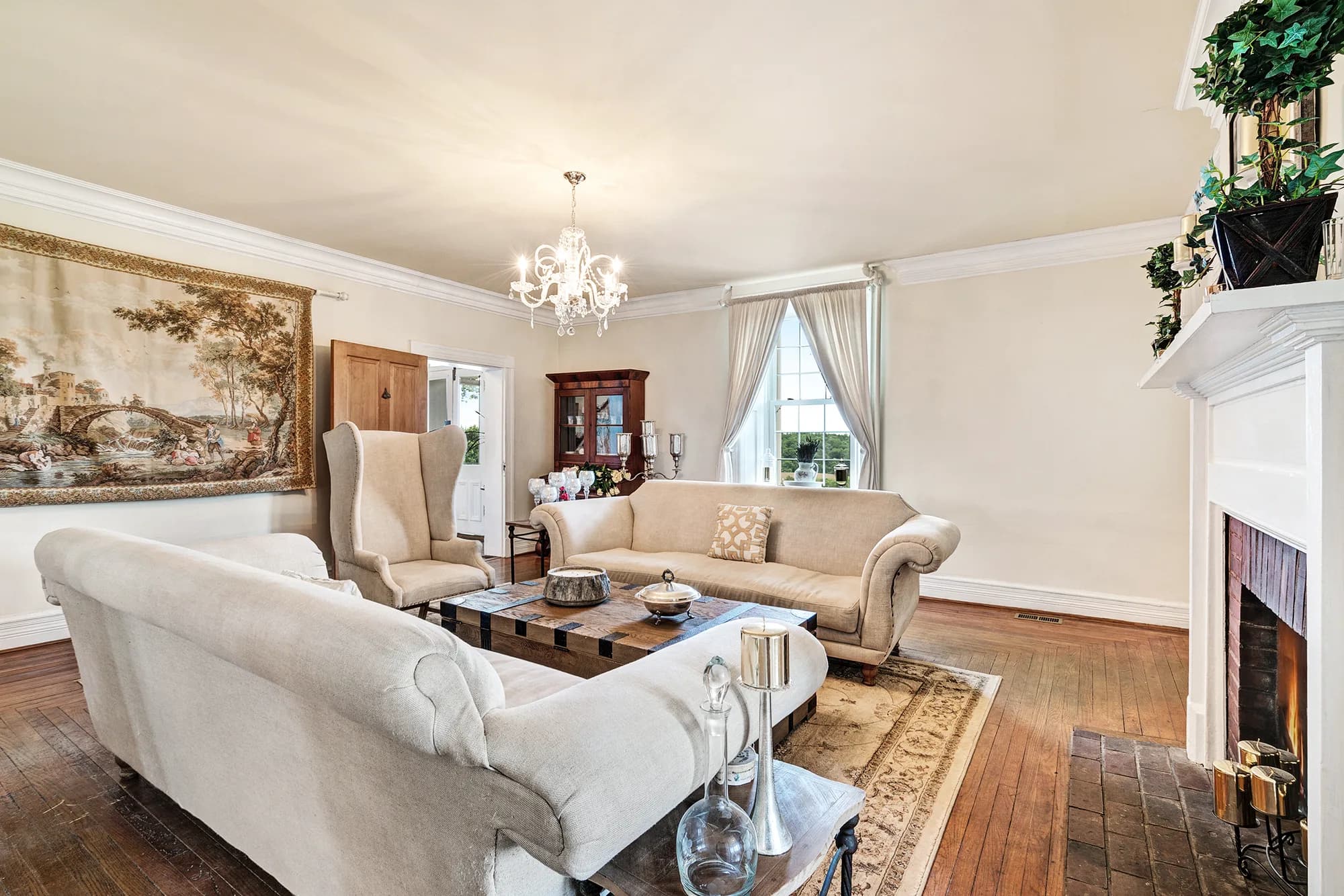 Elegant cream sitting room with fireplace, chandelier, and tapestry at Rixey Manor historic estate